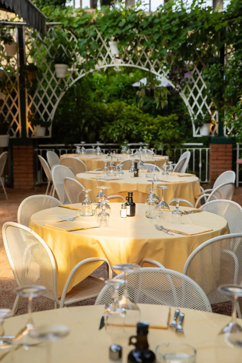 Il giardino di Ribot a San Siro: tavoli con le tovaglie gialle sotto un arco di glicine, sedie bianche
